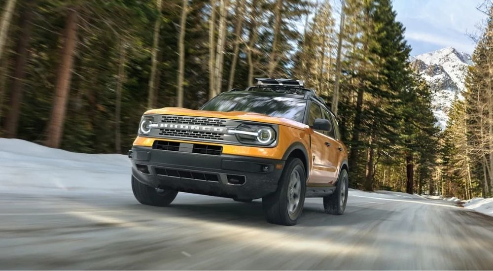 A yellow 2024 Ford Bronco Sport for sale is shown driving on a snowy road