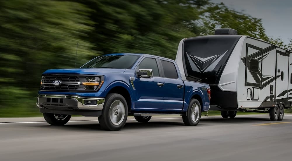 A blue 2025 Ford F-150 for sale near Poughkeepsie towing a camper.
