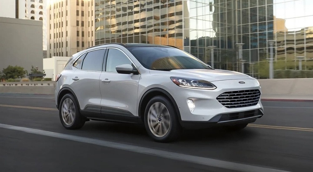 A white 2022 Ford Escape driving to a used car dealer.