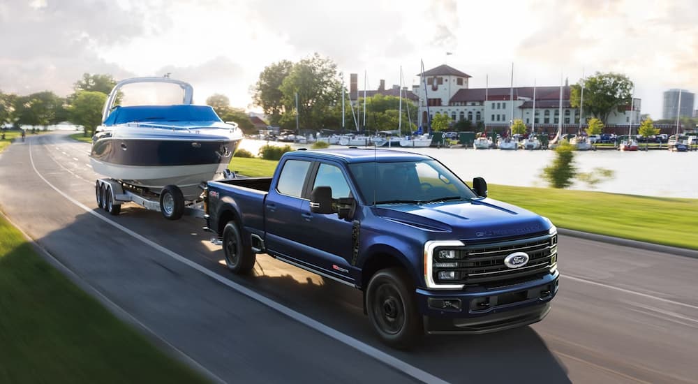 Blue 2026 Ford F-250 towing a boat down a street.