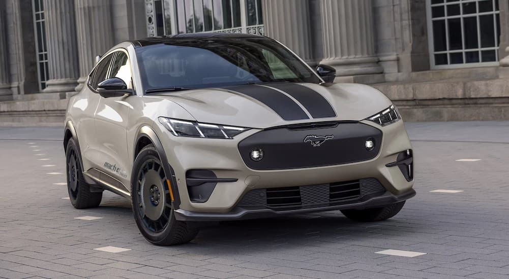 A tan 2026 Ford Mustang Mach-E parked near a building.