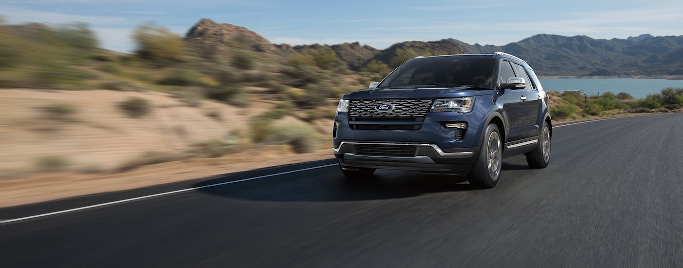 Blue 2018 Ford Explorer driving away from a lake.