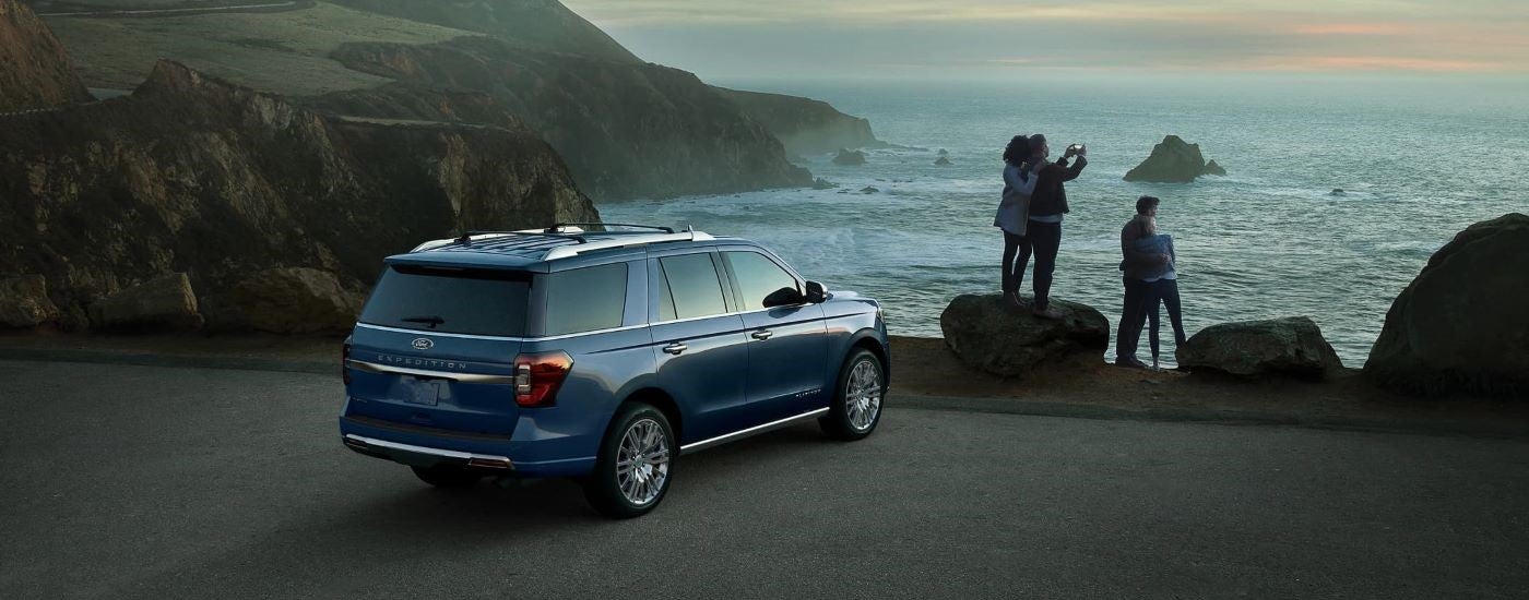 Rear of a blue 2023 Ford Expedition parked by water.