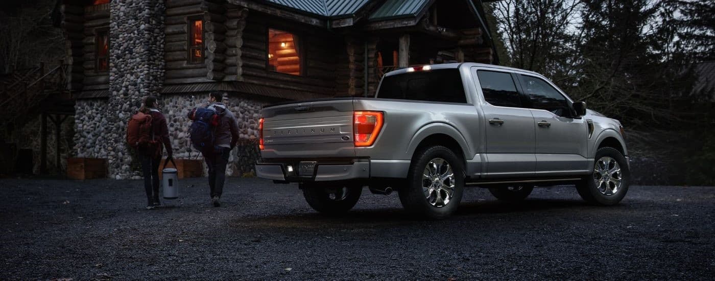 Silver 2023 Ford F-150 parked by a cabin.