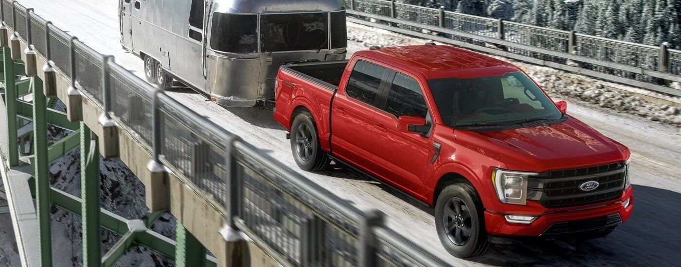 Red 2025 Ford F-150 Sport towing an airstream cabin across a bridge.