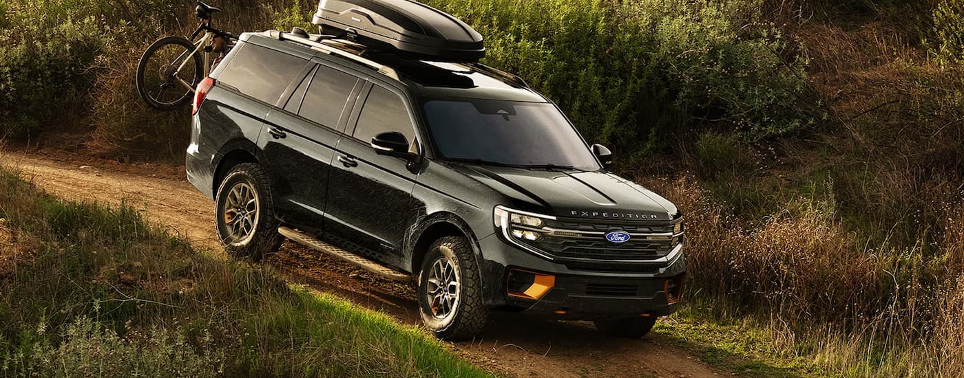 Black 2024 Ford Expedition driving off-road down a hill.
