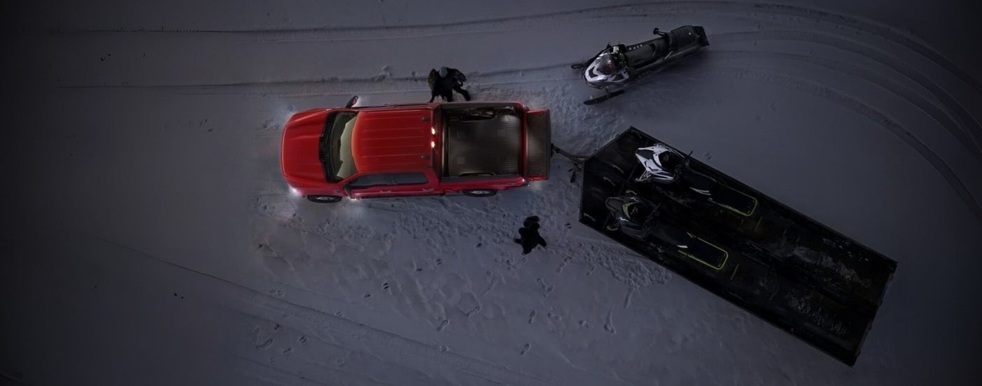 Snowmobiles near a red 2022 Ford F-150.