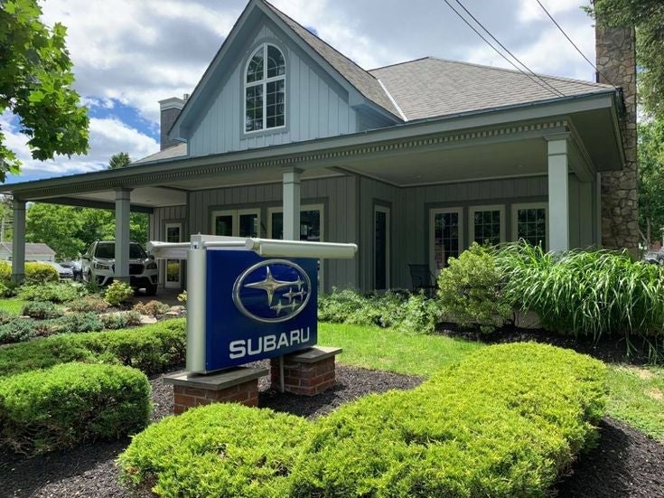 Subaru dealership in a house-style building surrounded by greenery.