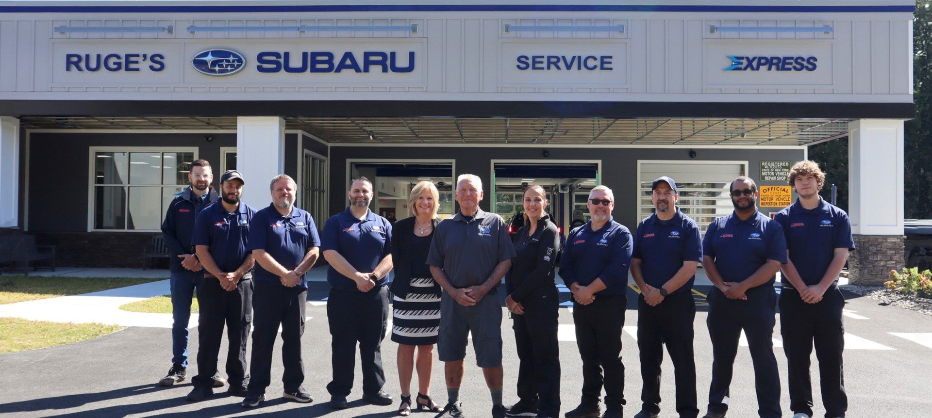 Subaru service team standing in front of the service center building.